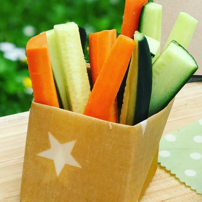 Ein Becher mit bunten Gemüsesticks: Karotten, Gurken und Zucchini.