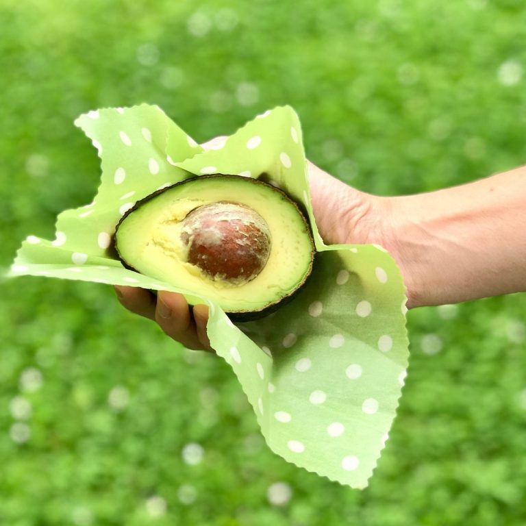Eine halbe Avocado in einem grünen, gepunkteten Bienenwachstuch.