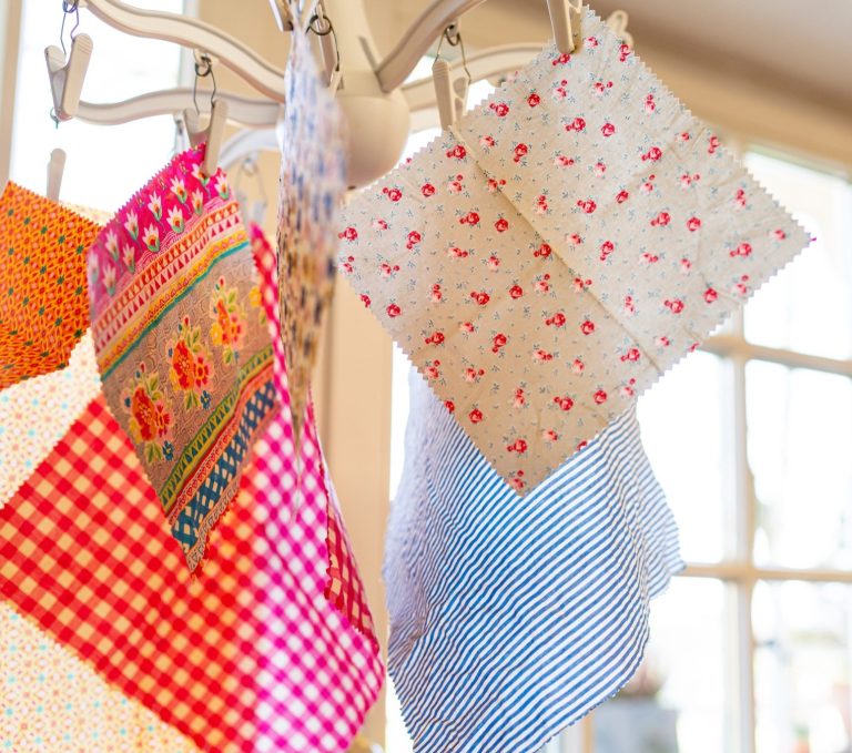 Bunte Bienenwachstücher in verschiedenen Mustern hängen an einem Haken und werden an der Luft getrocknet.