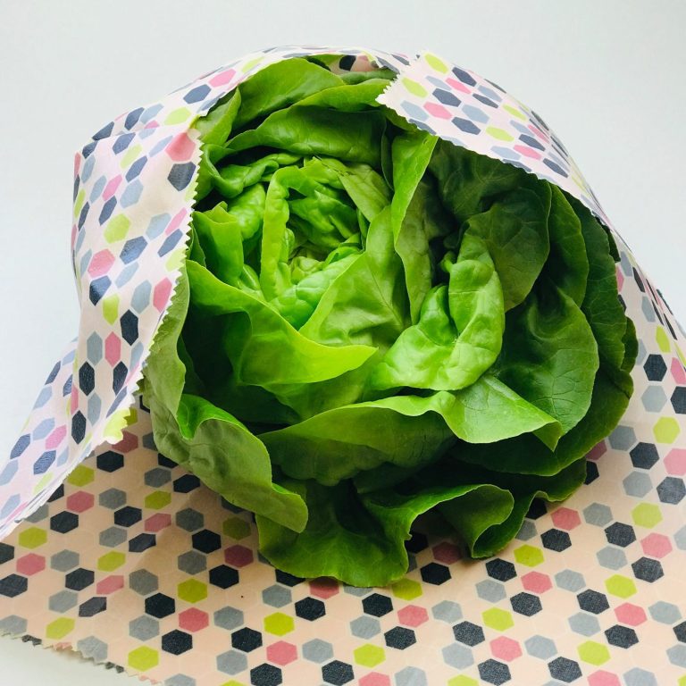 Ein Kopf frischer, grüner Salat in buntem, gepunktetem Bienenwachstuch XL.