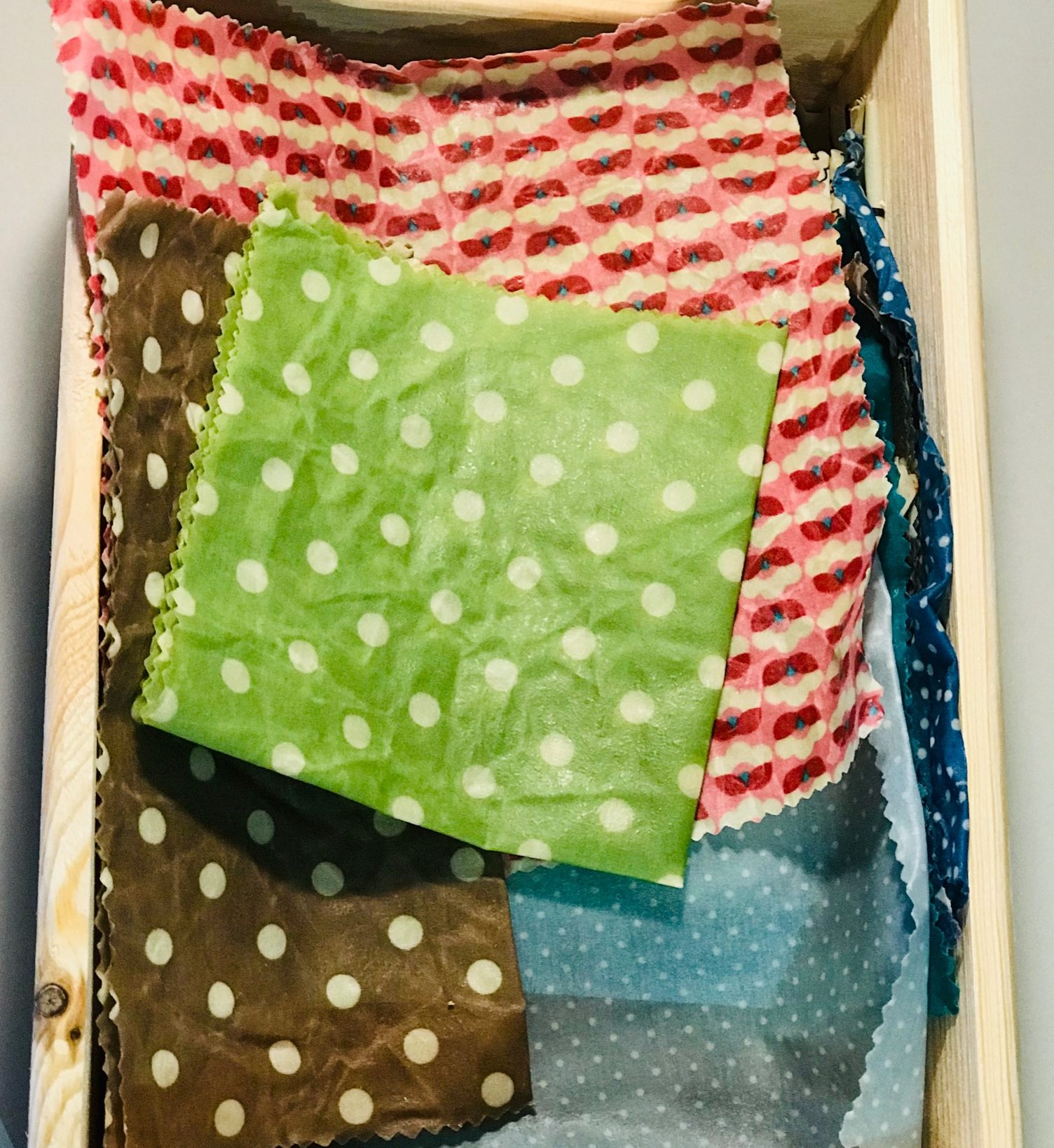 Bunte zusammengefaltete Bienenwachstücher mit verschiedenen Mustern in einer Holzbox.